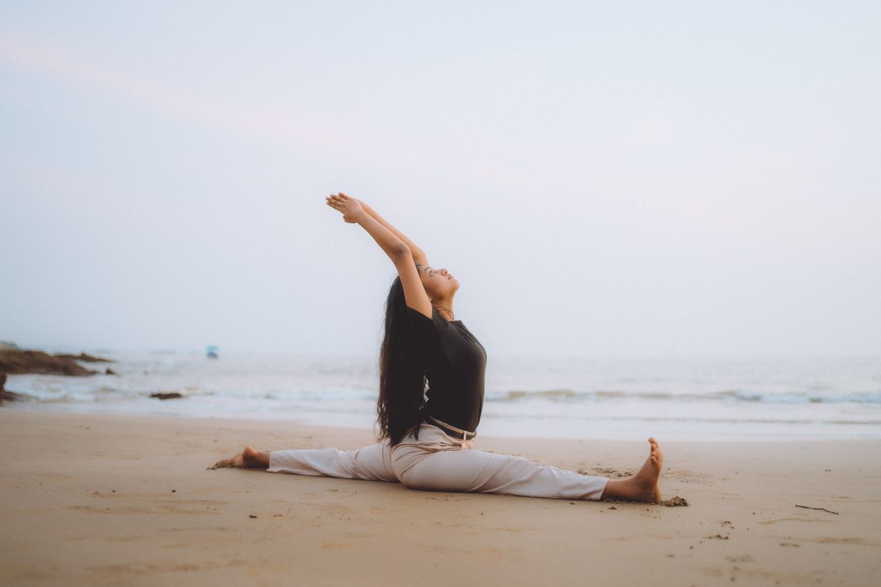 services-img Serene beach yoga session at sunrise with woman performing splits, embodying calm and balance.
